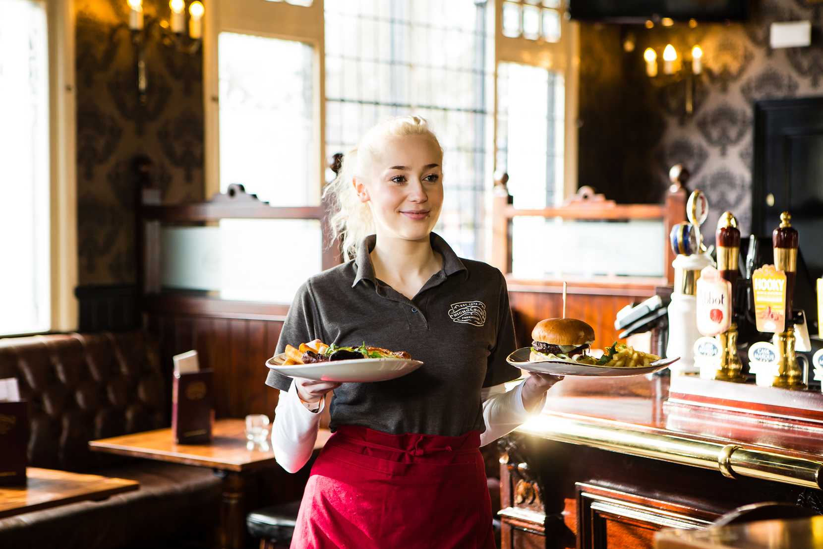 A team member at Nicholson's carries two plates through the pub to waiting guests.
