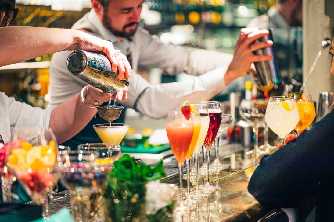 Mixologists are pouring cocktails at Browns. In front of them, all kinds of cocktails are lined up.