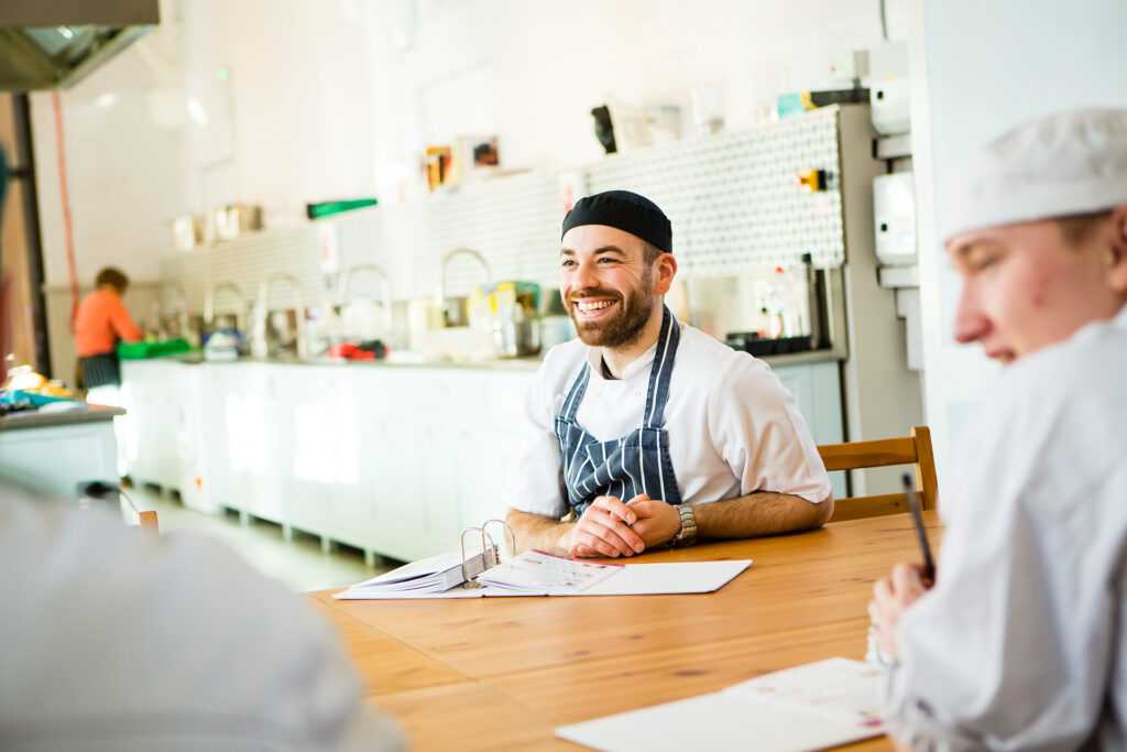 Two team members from the kitchen are sitting at a table, smiling.