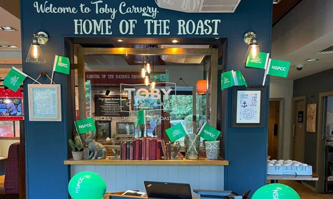 The entrance to a Toby Carvery, decorated in green NSPCC flags and balloons.