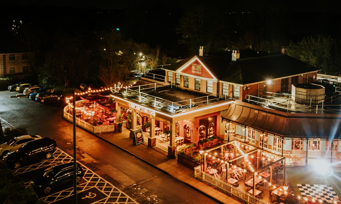 An external shot of the restaurant's exterior, at night time. The building has a warm glow from all the lights up around it.