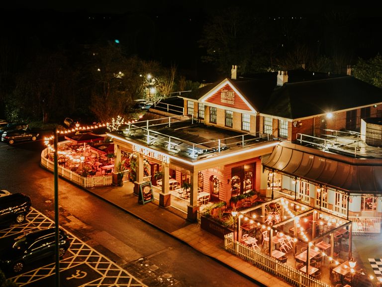 An external shot of the restaurant's exterior, at night time. The building has a warm glow from all the lights up around it.