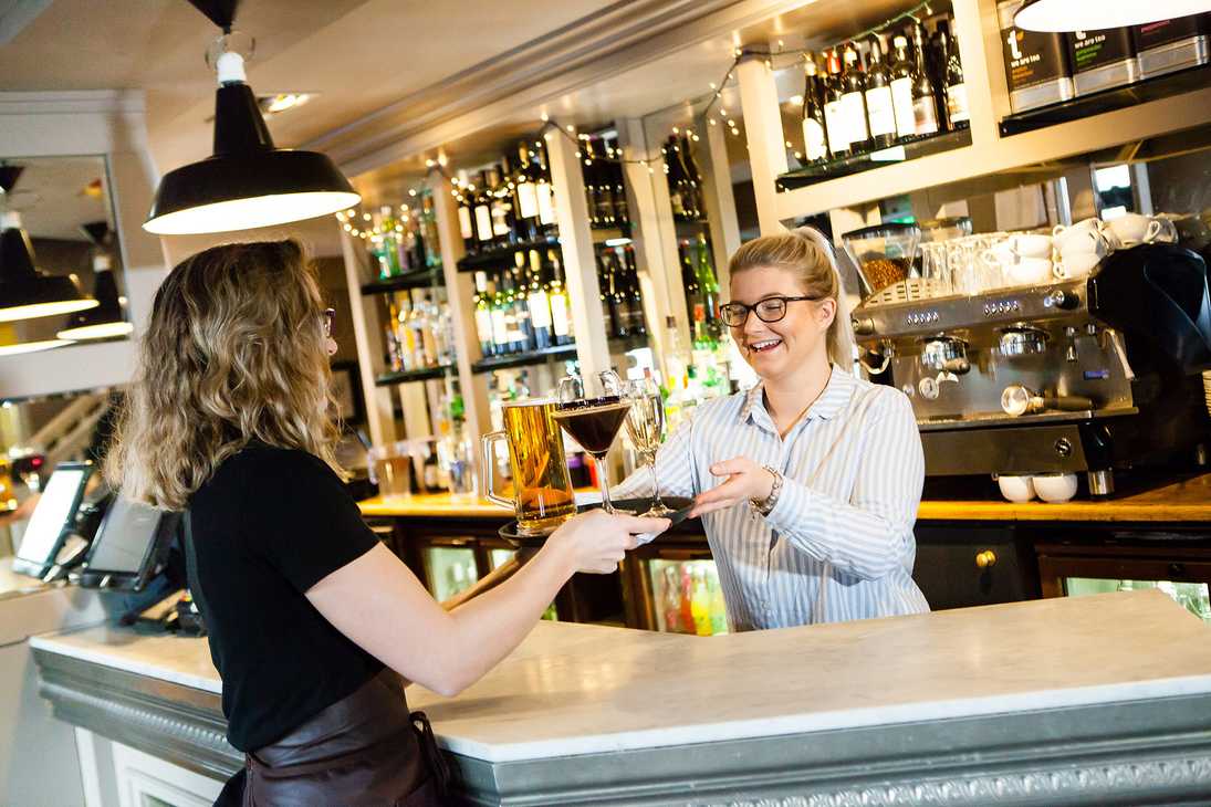 A guest is taking a tray of frinks from a smiling team member in a shirt.