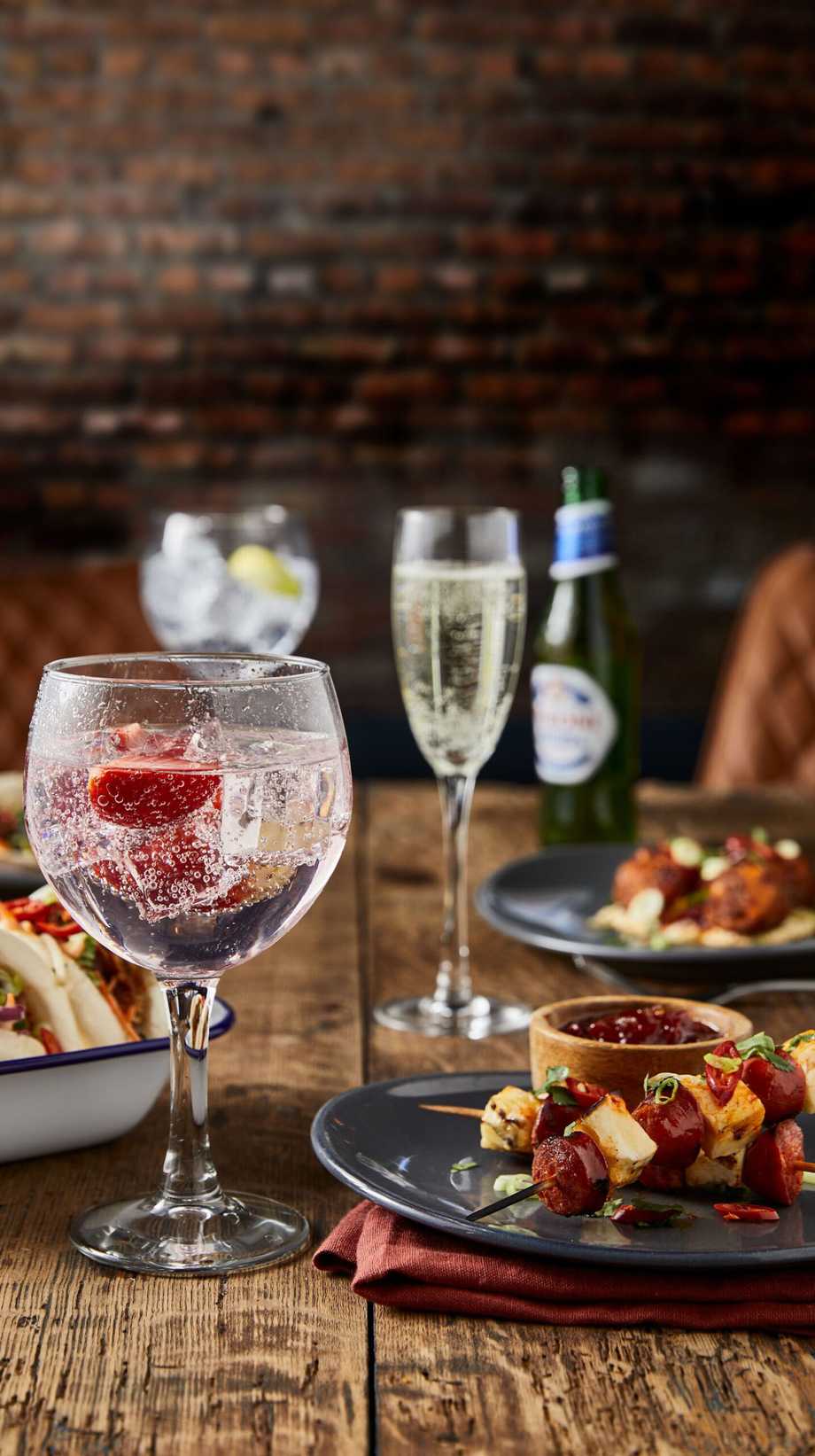 A table of food and drinks has been laid, with a large glass in the foreground, complete with ice and fruit.