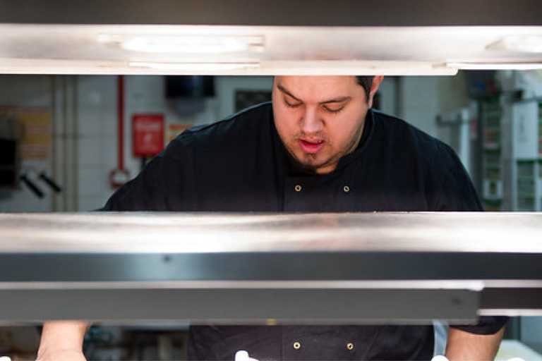 A chef is hard at work in the kitchen, wearing a black shirt.