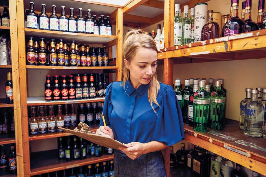 A woman stocktaking an assortment of drinks.