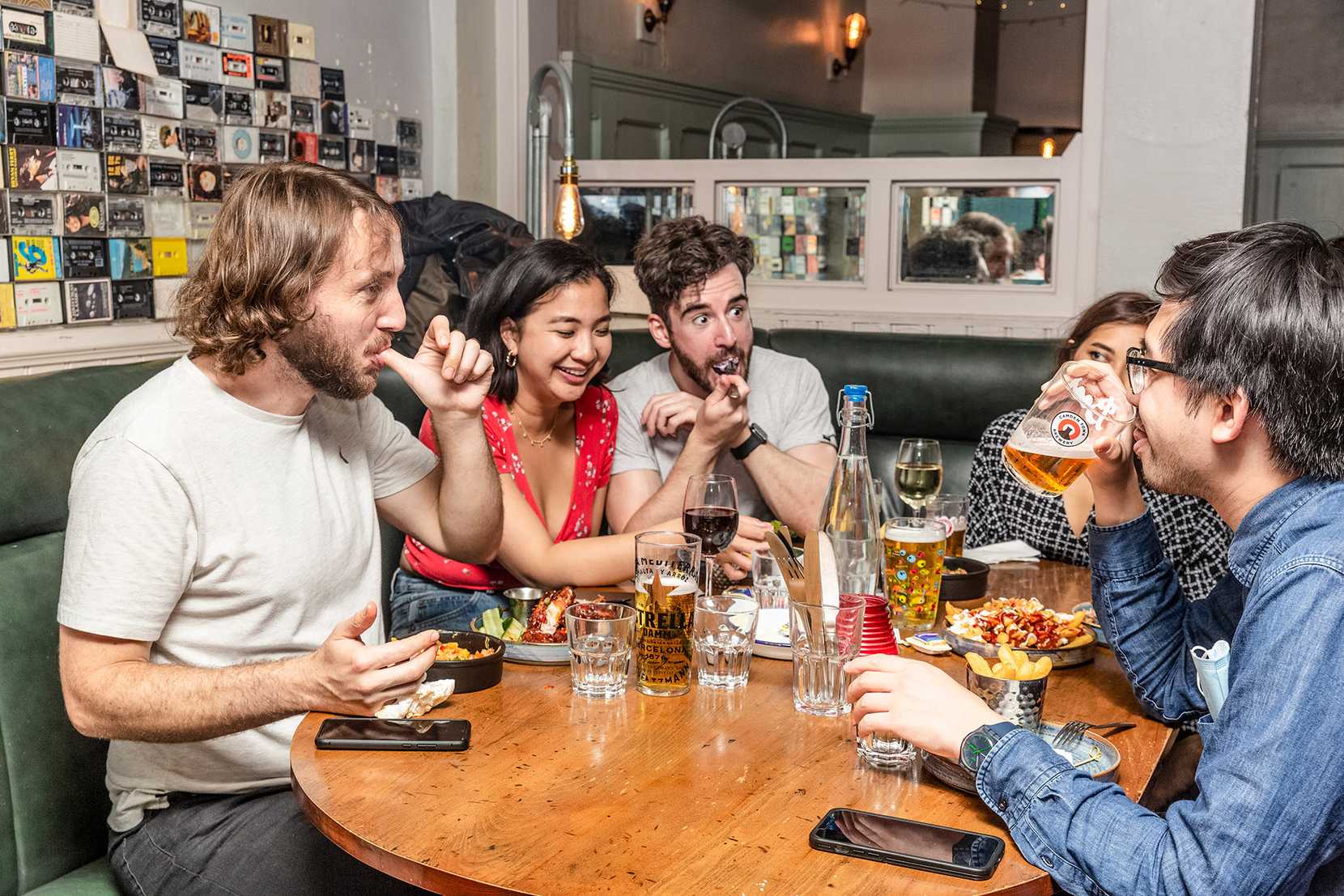 A table of friends are chatting while drinking and laughing.