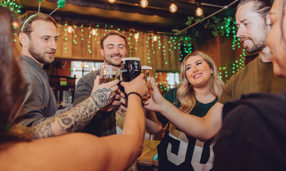 A group of people toasting in pub decorated with a St Patrick's theme