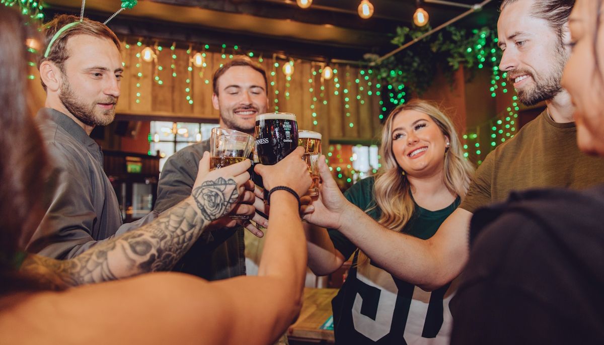 A group of people toasting in pub decorated with a St Patrick's theme