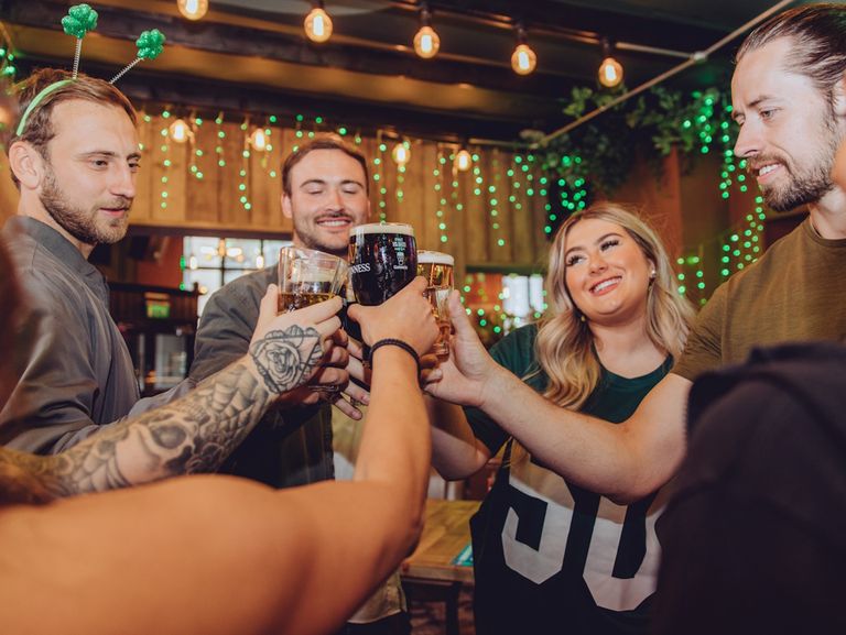 A group of people toasting in pub decorated with a St Patrick's theme