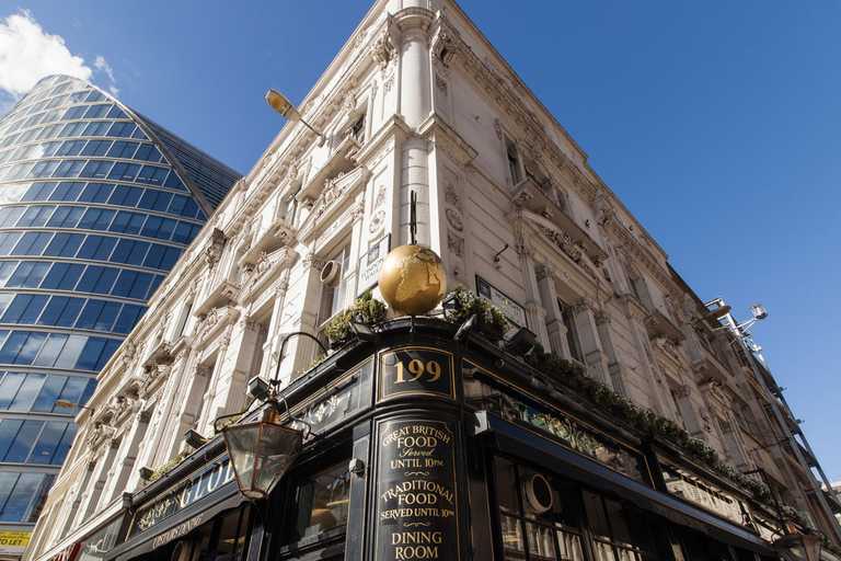 An exterior shot of The Globe pub, angled upwards, contrasting with a modern, glass building and blue sky.