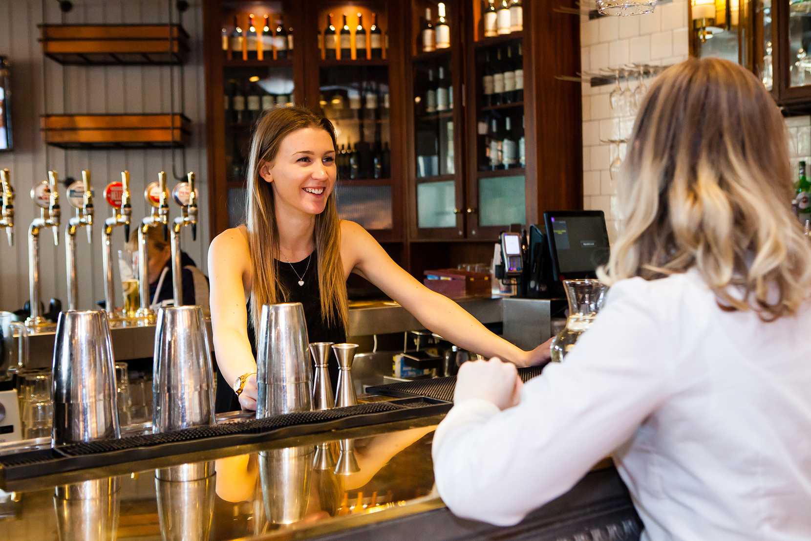 A guest smiles across the bar at the team member who's serving them.