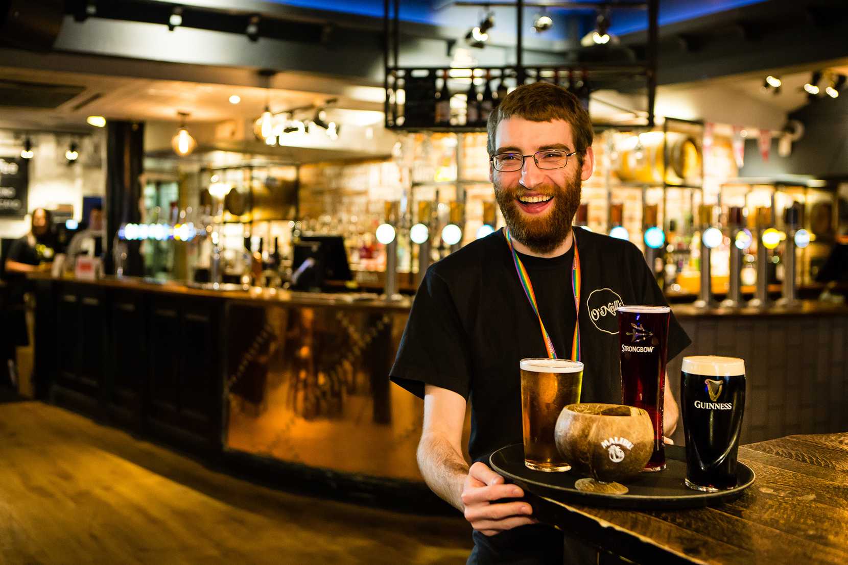 A tray of drinks is being placed onto a table by a smiling team member.